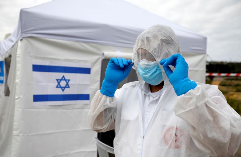 A paramedic adjusts his protective suit as he prepares outside a special polling station set up by Israel's election committee so Israelis under home-quarantine, such as those who have recently travelled back to Israel from coronavirus hot spots can vote in Israel's national election, in Ashkelon, I (photo credit: REUTERS/AMIR COHEN)