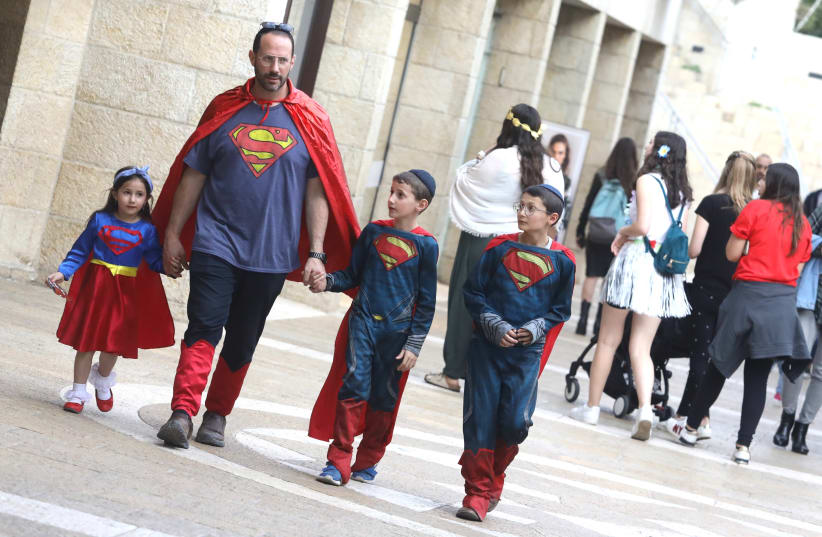 A Jewish father and his children wearing their Purim costumes, in this case, inspired by the fictional character of Superman   (photo credit: MARC ISRAEL SELLEM)