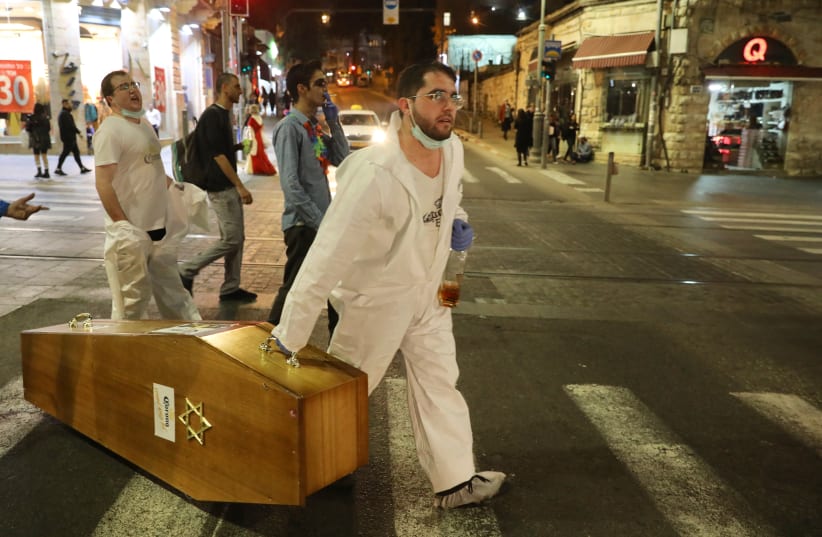 Jerusalem residents enjoy the holiday of Purim while wearing costumes that poke fun at the coronavirus pandemic, pretending to bury the virus (photo credit: MARC ISRAEL SELLEM)