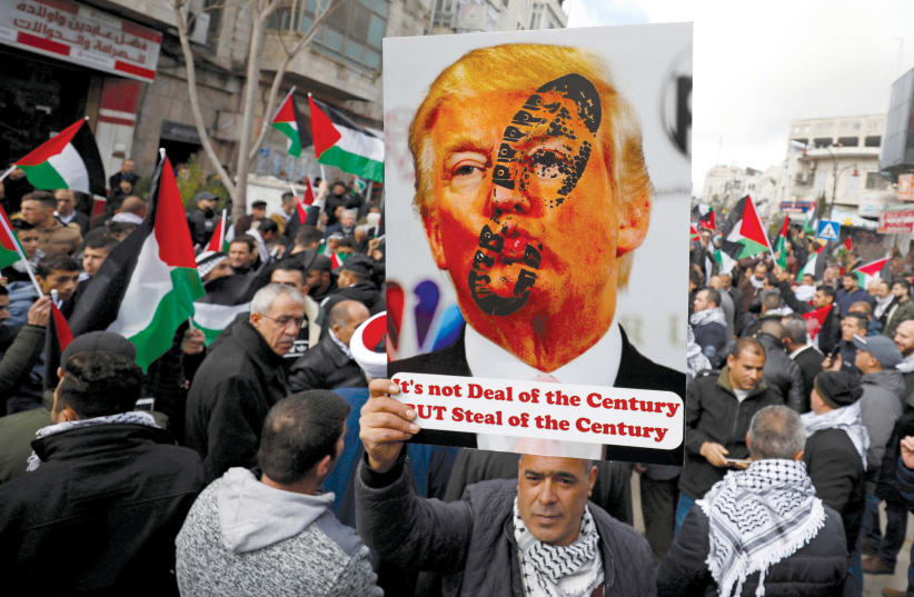 A PALESTINIAN demonstrator holds an anti-US President Donald Trump poster during a rally in support of Abbas and against Trump’s Middle East peace plan, in Ramallah on February 11.  (photo credit: REUTERS)