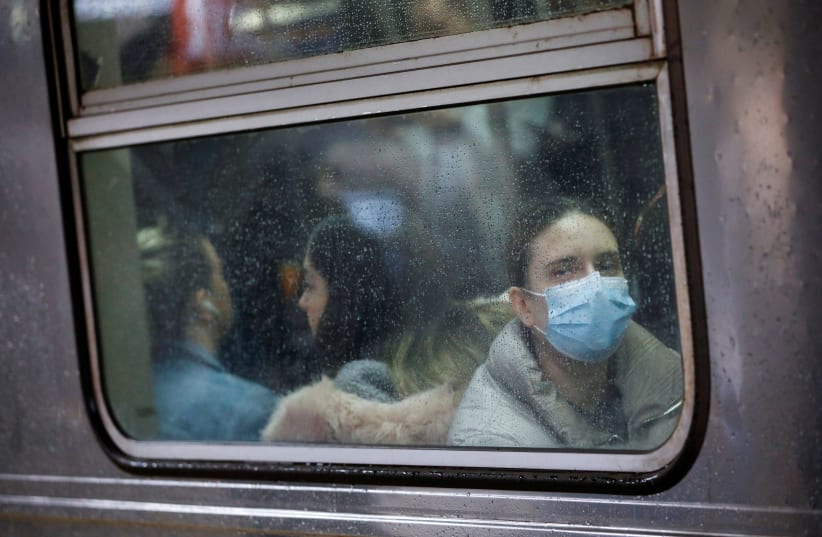 A woman wears a face mask on the subway as the coronavirus outbreak continued in Manhattan, New York City, New York, U.S., March 13, 2020 (photo credit: REUTERS/ANDREW KELLY)