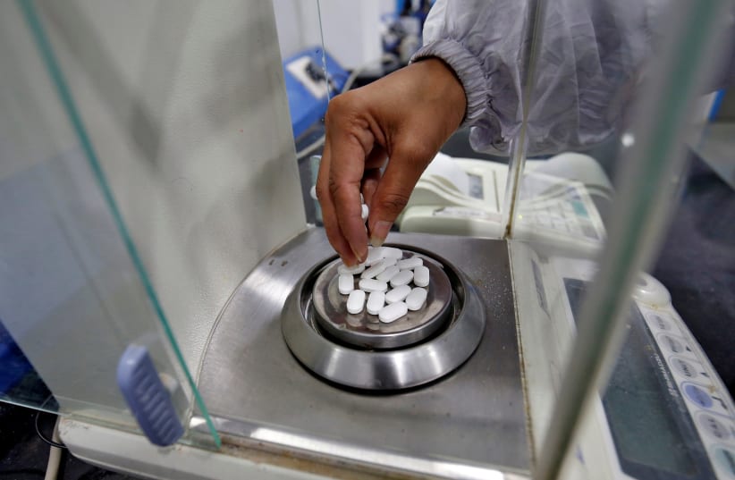 FILE PHOTO: A pharmacist checks weight of Paracetamol, a common pain reliever also sold as acetaminophen, tablets inside a lab of a pharmaceutical company on the outskirts of Ahmedabad, India, March 4, 2020 (photo credit: REUTERS/AMIT DAVE)
