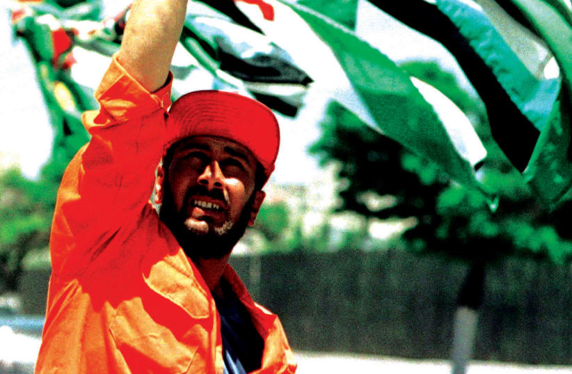 JORDANIAN man lifts the country’s flag at a celebration in the 1990s. (photo credit: REUTERS)