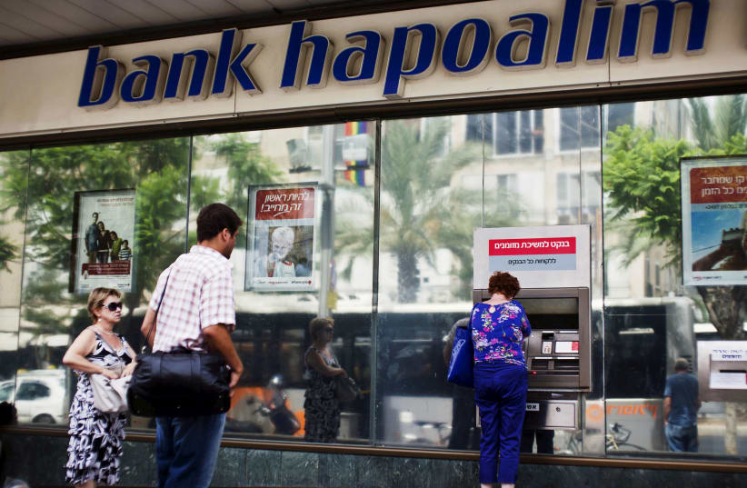 A woman uses an automated teller machine (ATM) outside a Bank Hapoalim branch in Tel Aviv, Israel May 30, 2013 (photo credit: REUTERS/NIR ELIAS/FILE PHOTO)