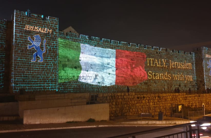 The Italian flag shown on the Old City walls of Jerusalem to show solidarity during the coronavirus outbreak (photo credit: ARNON BOSSANI)