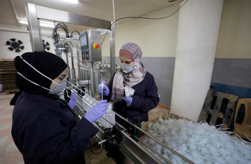 Palestinian women work in a sanitiser factory amid precautions against the coronavirus, in Hebron in the West Bank March 12, 2020 (photo credit: REUTERS/MUSSA QAWASMA)