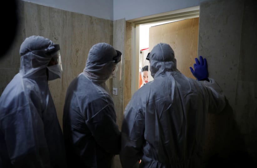 Health Ministry inspectors speak with a woman who is in self quarantine as a precaution against coronavirus spread in Hadera (photo credit: REUTERS)