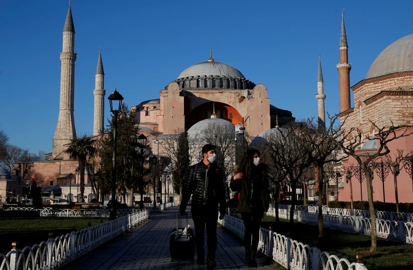 Tourists wearing protective face masks, due to coronavirus disease (COVID-19) concerns, stroll at Sultanahmet square in Istanbul, Turkey, March 17, 2020. (photo credit: REUTERS/KEMAL ASLAN)