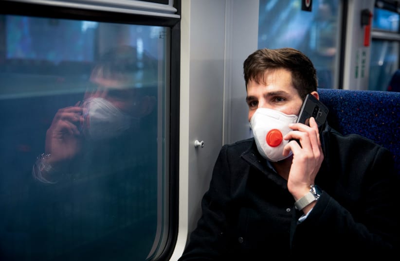 A man wears a face mask for fear of the coronavirus as he takes the train to Haifa, on March 17, 2020 (photo credit: YOSSI ALONI/FLASH90)