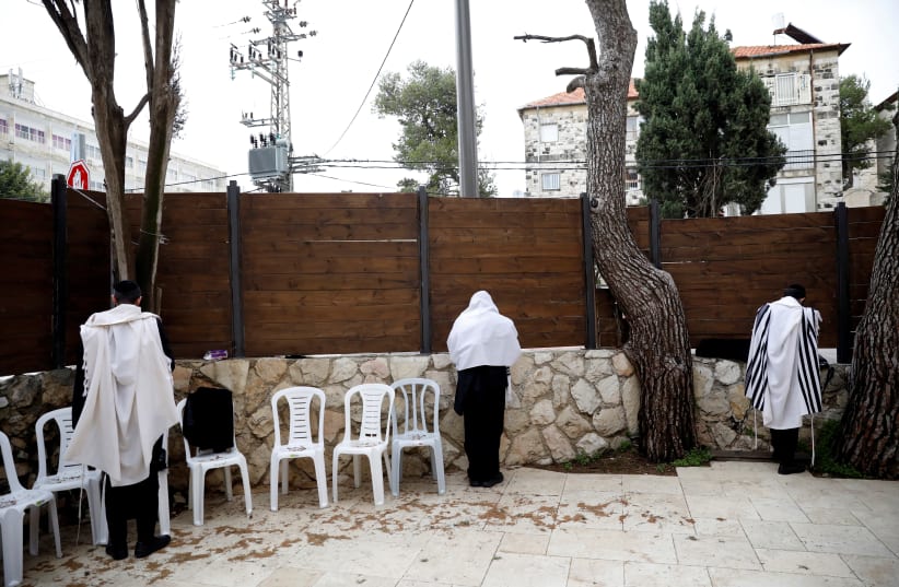 Jewish men wearing prayer shawls perform morning prayers in a courtyard of a synagogue in Jerusalem (photo credit: REUTERS)