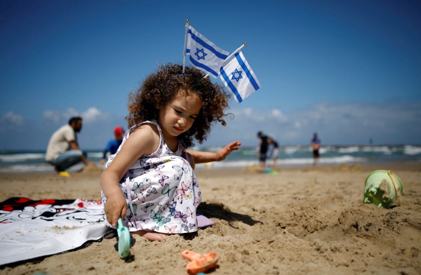 A girl plays on the beach as Israel celebrates its Independence Day marking the 71st anniversary of the creation of the state, in Tel Aviv, Israel May 9, 2019 (photo credit: REUTERS/CORINNA KERN)