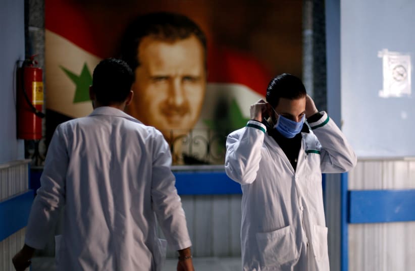 A health worker with a face mask walks inside a hospital in Syria (photo credit: REUTERS/OMAR SANADIKI)