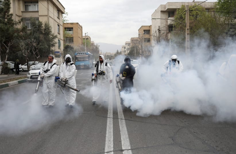 Members of firefighters wear protective face masks, amid fear of coronavirus disease (COVID-19), as they disinfect the streets, ahead of the Iranian New Year Nowruz, March 20, in Tehran, Iran March 18, 2020. (photo credit: WANA NEWS AGENCY/REUTERS)