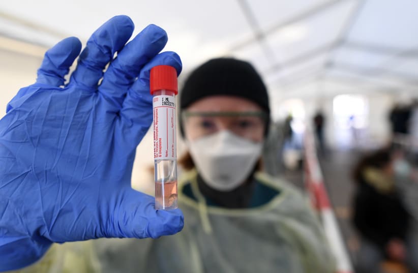 A medical employee presents a smear taken at a special corona test center for public service employees such as police officers, nurses and firefighters during a media presentation as the spread of the coronavirus disease (COVID-19) continues, in Munich, Germany, March 23, 2020 (photo credit: REUTERS/ANDREAS GEBERT)