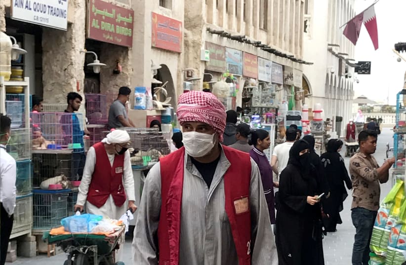 A man wears a protective face mask, following the outbreak of coronavirus, as he pushes a cart in souq Waqif in Doha, Qatar (photo credit: REUTERS)