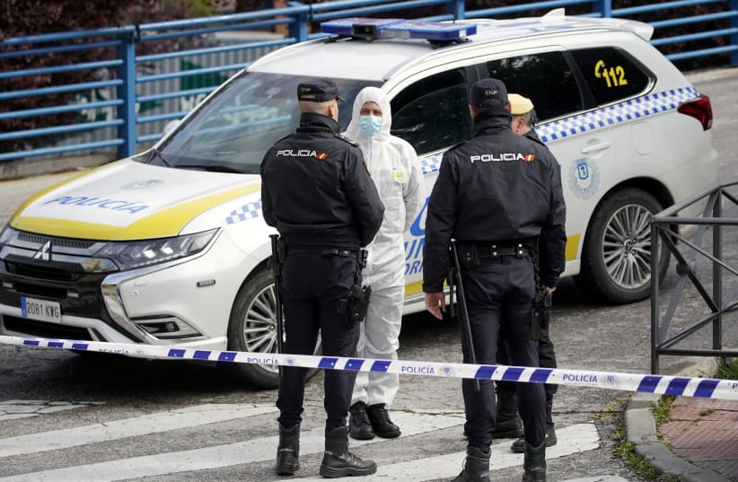 A member of the Spanish army talks with Spanish National policemen outside an ice rink which will be used as a morgue, during the coronavirus disease (COVID-19) outbreak in Madrid, Spain, March 24, 2020 (photo credit: REUTERS)