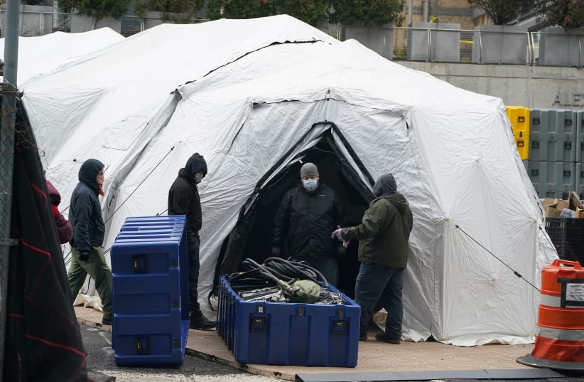 Workers construct what is believed to be a makeshift morgue behind a hospital during the outbreak of coronavirus disease in New York City (photo credit: CARLO ALLEGRI/REUTERS)