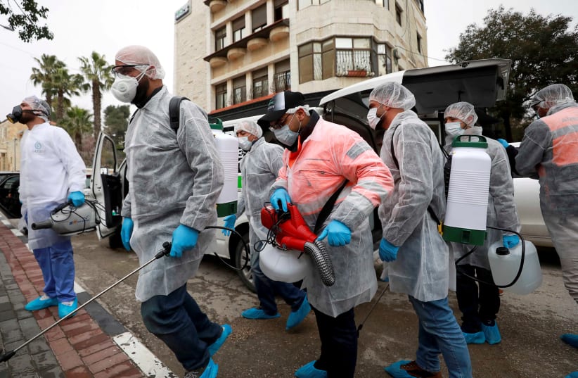FILE PHOTO: Palestinian workers make their way to disinfect religious sites as preventive measures against the coronavirus, in Ramallah in the in the West Bank March 7, 2020 (photo credit: REUTERS/MOHAMAD TOROKMAN/FILE PHOTO)