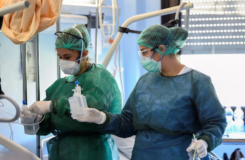 Medical staff wearing protective masks, glasses and suits treat a patient suffering from coronavirus disease (COVID-19) in an intensive care unit at the Oglio Po hospital in Cremona, Italy March 19, 2020 (photo credit: REUTERS/FLAVIO LO SCALZO)