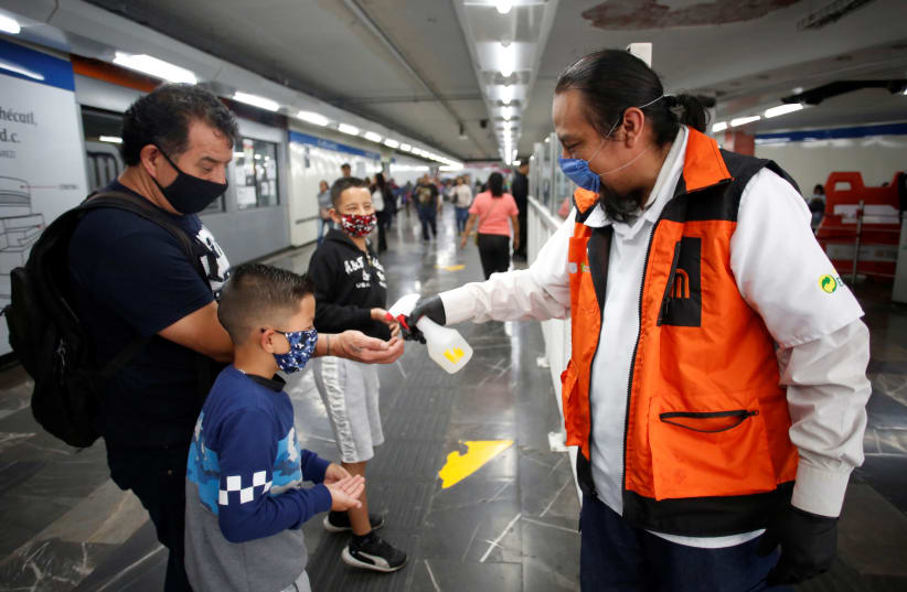 A METRO employee sprays disinfectant toward commuters inside the metro installation as the coronavirus disease (COVID-19) outbreak continues, in Mexico City last week (photo credit: GUSTAVO GRAF/REUTERS)