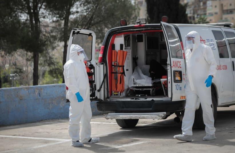 Magen David Adom workers wearing protective clothing, as a preventive measure against the coronavirus seen as they evacuating a man with suspicion for Coronavirus at Shaarei Tsedek hospital in Jerusalem on March 30, 2020 (photo credit: YOSSI ZAMIR/FLASH90)
