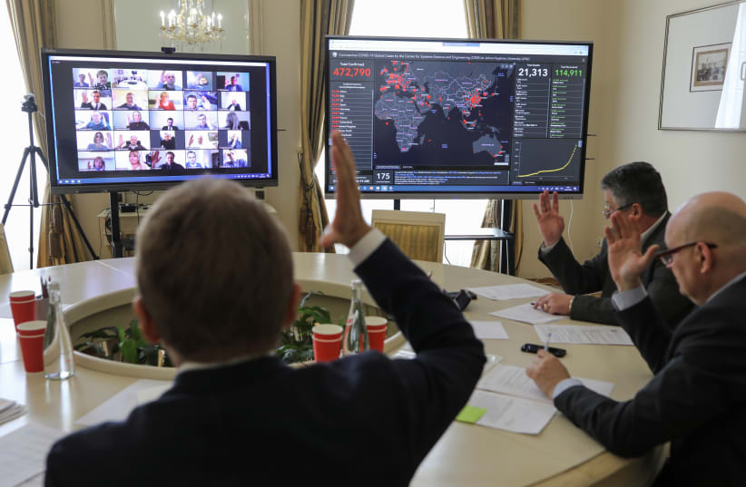 Members of the city commission to prevent the spread of coronavirus disease (COVID-19) vote during a meeting via Zoom video link in Lviv, Ukraine March 26, 2020. (photo credit: REUTERS/ROMAN BALUK)