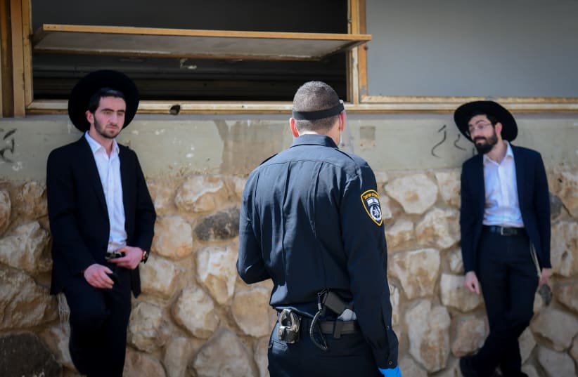 Israeli police officers take out ultra-Orthodox Jewish men from the Ponevezh Yeshiva in Bnei Brak, as part of an effort to enforce lockdown in order to prevent the spread of the coronavirus, April 2, 2020. (photo credit: FLASH90)