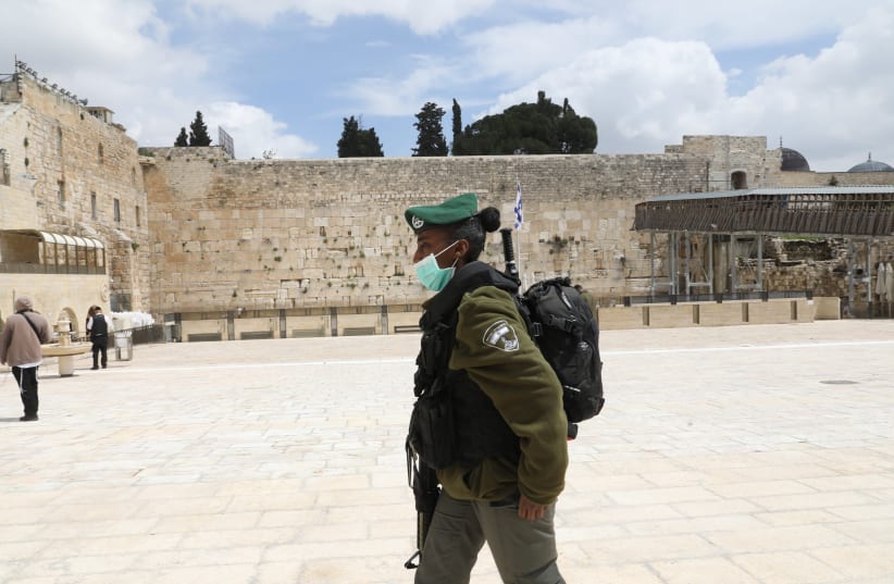 A lone soldier walks past the Western Wall amid the coronavirus pandemic. (photo credit: MARC ISRAEL SELLEM)