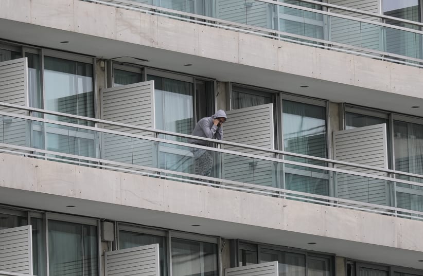 A man, who flew back from Spain, is seen on the balcony of a hotel where he and other passengers were placed in a two-week quarantine, after the Greek government imposed a nationwide lockdown to contain the spread of the coronavirus disease (COVID-19), in Athens, Greece, March 23, 2020 (photo credit: REUTERS/COSTAS BALTAS)