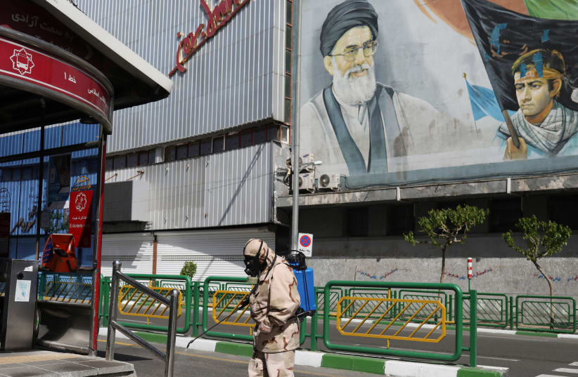 A volunteer from Basij forces sprays disinfectant as he sanitizes a bus station, amid coronavirus disease fears, in Tehran, Iran (photo credit: WANA (WEST ASIA NEWS AGENCY)/ALI KHARA VIA REUTERS)