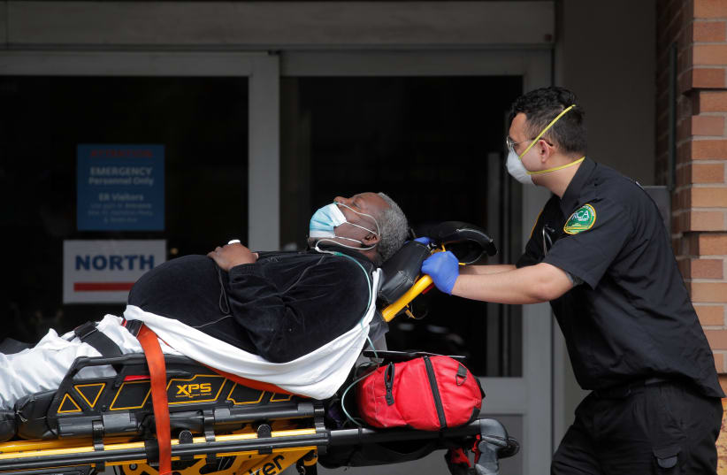 Paramedics take a patient into emergency center at Maimonides Medical Center during the outbreak of the coronavirus disease (COVID-19) in the Brooklyn borough of New York City, New York, U.S., April 7, 2020 (photo credit: BRENDAN MCDERMID/REUTERS)