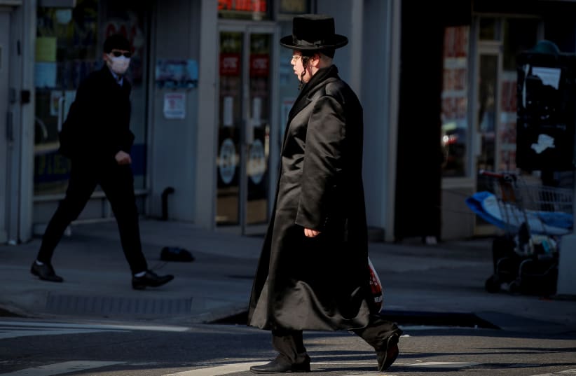 Members of the Hasidic Jewish community walk through the Borough Park neighborhood, during the outbreak of the coronavirus disease (COVID19) in the Brooklyn borough of New York, U.S., April 8, 2020 (photo credit: REUTERS/BRENDAN MCDERMID)