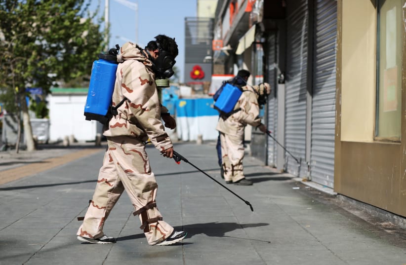Volunteers from Basij forces wearing protective suits and face masks spray disinfectant in the streets, amid the coronavirus disease (COVID-19) fears, in Tehran, Iran April 3, 2020 (photo credit: WANA (WEST ASIA NEWS AGENCY)/ALI KHARA VIA REUTERS)