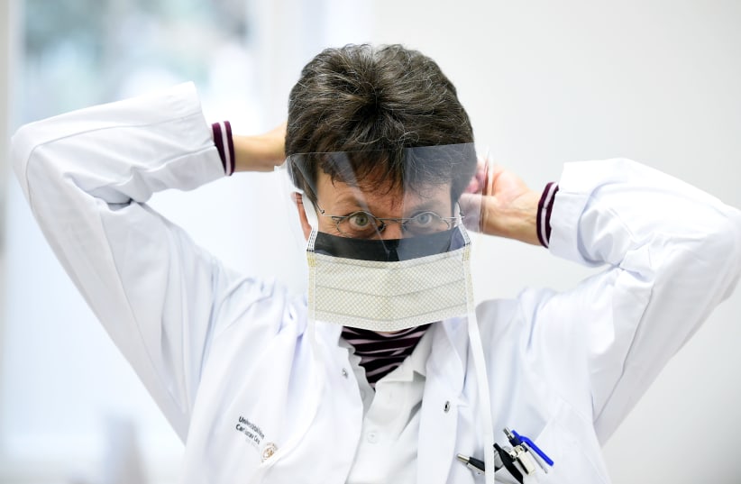 Chief doctor Katja de With puts on a protective mask during a media event in the newly opened coronavirus disease (COVID-19) clearing-up centre in Dresden (photo credit: REUTERS)