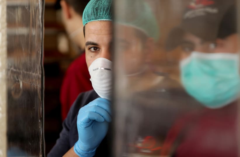  Palestinians, wearing masks as a preventive measure against the coronavirus disease, work in a bakery in Gaza City (photo credit: REUTERS/MOHAMMED SALEM)