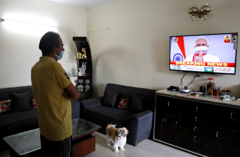 A man watches India's Prime Minister Narendra Modi's address to the nation on a television announcing the extension of a nationwide lockdown till May 3, to limit the spreading of coronavirus disease (COVID-19), in in New Delhi, India, April 14, 2020. (photo credit: REUTERS/ANUSHREE FADNAVIS)