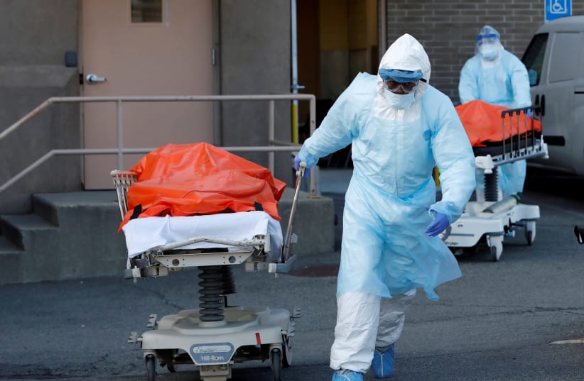 Healthcare workers wheel the bodies of deceased people from the Wyckoff Heights Medical Center during the outbreak of the coronavirus disease (COVID-19) in the Brooklyn borough of New York City, New York, U.S., April 4, 2020 (photo credit: REUTERS)