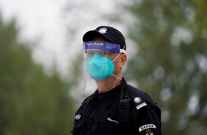 Security guard wearing face mask and face shield is seen in Wuhan (photo credit: REUTERS)
