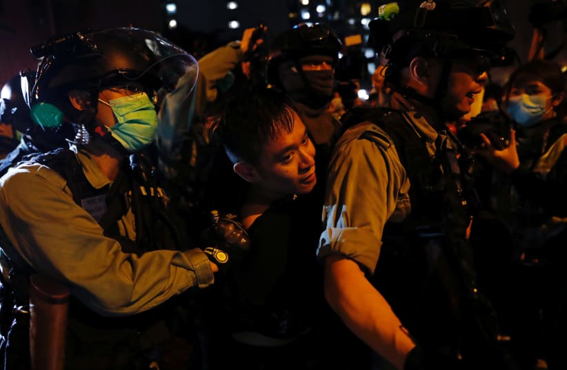 An anti-government protester is detained by riot police after attending a vigil to mourn student's death, in Hong Kong, China March 8, 2020.  (photo credit: REUTERS)