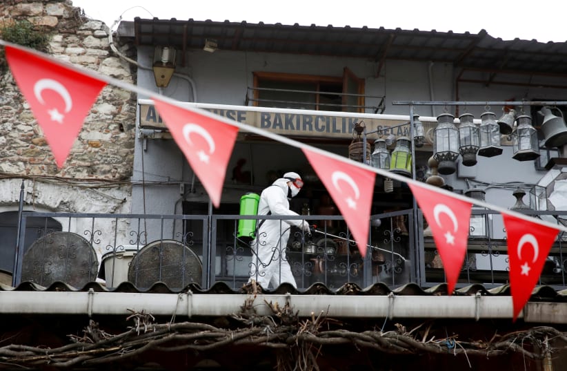 FILE PHOTO: A worker in a protective suit sprays disinfectant at Grand Bazaar, known as the Covered Bazaar, to prevent the spread of coronavirus disease (COVID-19), in Istanbul, Turkey, March 25, 2020 (photo credit: REUTERS/UMIT BEKTAS/FILE PHOTO)