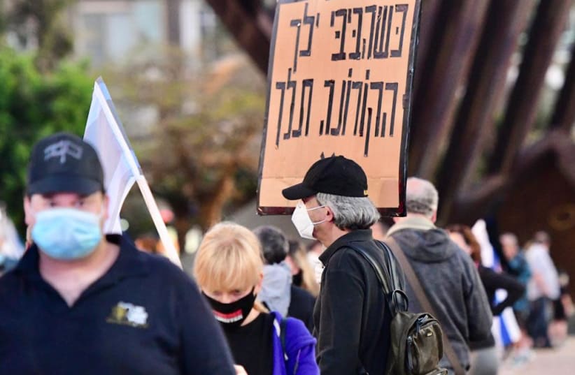 A man in the Black Flag protest on Sunday April 19 2020 in Tel Aviv, the sign says 'When [Prime Minister Benjamin Netanyahu] Bibi will go, the coronavirus will go  (photo credit: AVRAHAM SASSONI)