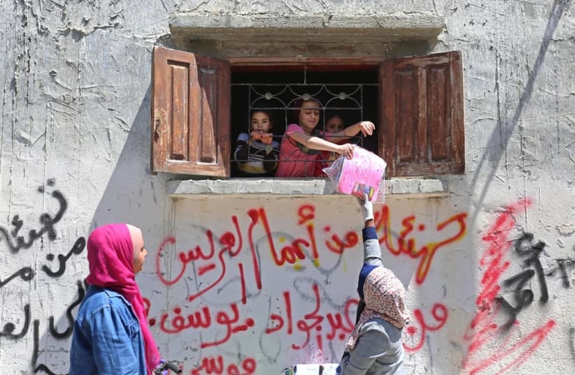 Eilya Alzra’ei (right) and Riham Basheer distributing storybooks, paper, and crayons, Deir Albalah camp (photo credit: Courtesy)