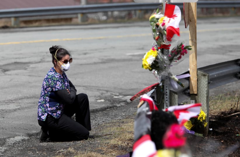 Care worker and first responder, Alicia Cunningham, looks at a makeshift memorial for Royal Canadian Mounted Police (RCMP) Constable Heidi Stevenson, who was shot dead during a killing spree. April 22, 2020 (photo credit: REUTERS/TIM KROCHAK)