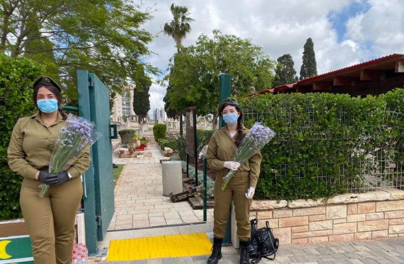 IDF soldiers wearing masks against the coroanvirus and holding flowers at the gate to a military graveyard ahead of Memorial Day  (photo credit: IDF SPOKESPERSON'S UNIT)