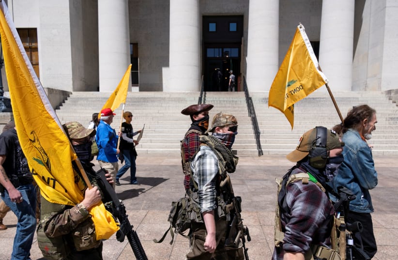 A militia group from Ohio protests against the state's extended stay-at-home order to help slow the spread of the Coronavirus disease (COVID-19) demonstrate at the Capitol building in Columbus, Ohio, U.S. April 20, 2020. (photo credit: REUTERS/SETH HERALD)
