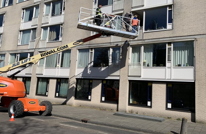 Relatives of Fiet Aussen get ready to meet her from a crane outside the window of her Jewish nursing home in Amsterdam, April 15, 2020 (photo credit: COURTESY OF RIWAL HOLDING GROUP/JTA)