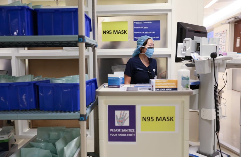 A member of medical staff wearing a protective face mask, works at an N95 face mask collection point, amid the coronavirus disease (COVID-19) outbreak, at the Cleveland Clinic hospital in Abu Dhabi, United Arab Emirates, April 20, 2020 (photo credit: REUTERS/CHRISTOPHER PIKE)
