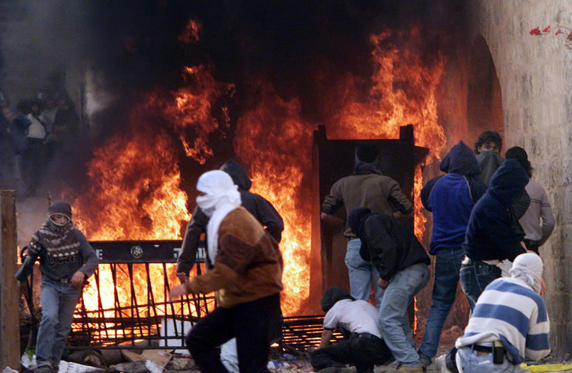 Palestinians man a burning barricade on the Via Dolorosa in Jerusalem's Old City as they fight violent clashes with Israeli Border Police, December 2000 (photo credit: REUTERS)