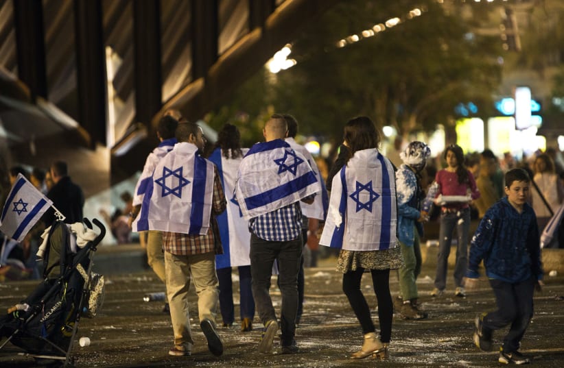 People covered with Israeli national flags walk onto Rabin square to take part in the celebrations for Israel's Independence Day at its 65th anniversary of the creation of the state in Tel Aviv (photo credit: NIR ELIAS / REUTERS)