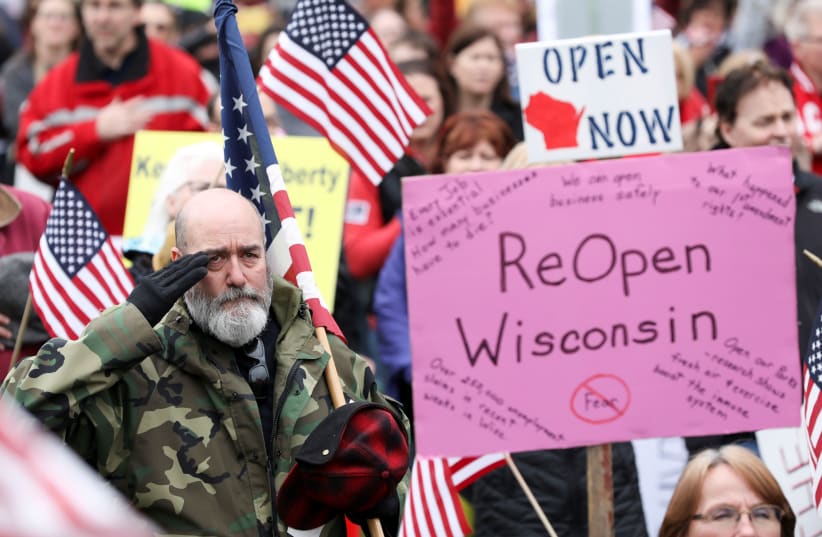 Protesters against the state's extended stay-at-home order to help slow the spread of the coronavirus disease (COVID-19) demonstrate at the Capitol building in Madison, Wisconsin, US April 24, 2020.  (photo credit: DANIEL ACKER/REUTERS)